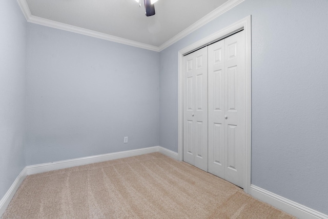 unfurnished bedroom featuring crown molding, carpet, ceiling fan, and a closet