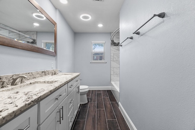 full bathroom featuring vanity, tiled shower / bath, and toilet