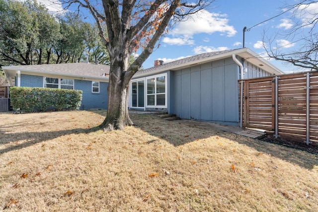 back of house with central AC unit and a lawn