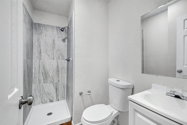 bathroom with vanity, toilet, and a tile shower