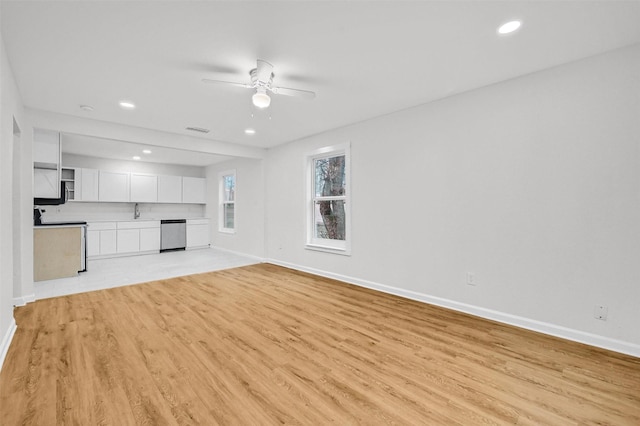 unfurnished living room featuring ceiling fan, sink, and light wood-type flooring