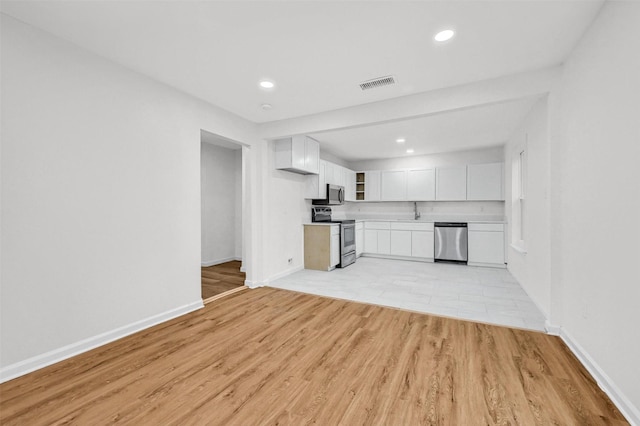 kitchen featuring sink, stainless steel appliances, light hardwood / wood-style floors, and white cabinets