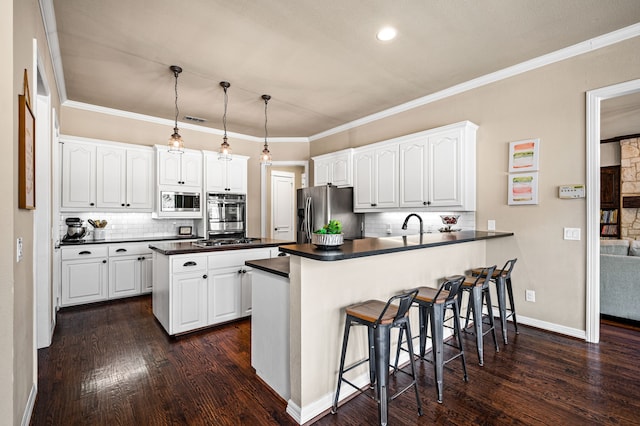 kitchen featuring appliances with stainless steel finishes, pendant lighting, white cabinets, and kitchen peninsula