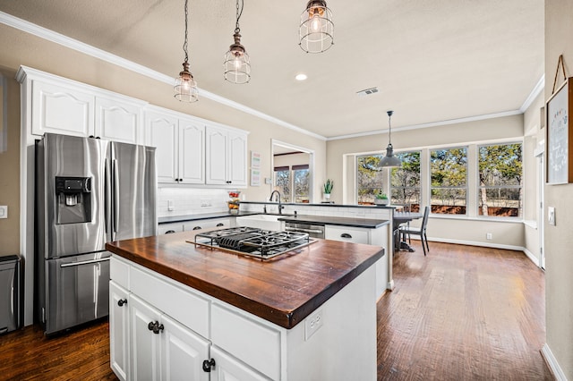 kitchen featuring wood counters, white cabinetry, a center island, hanging light fixtures, and stainless steel appliances