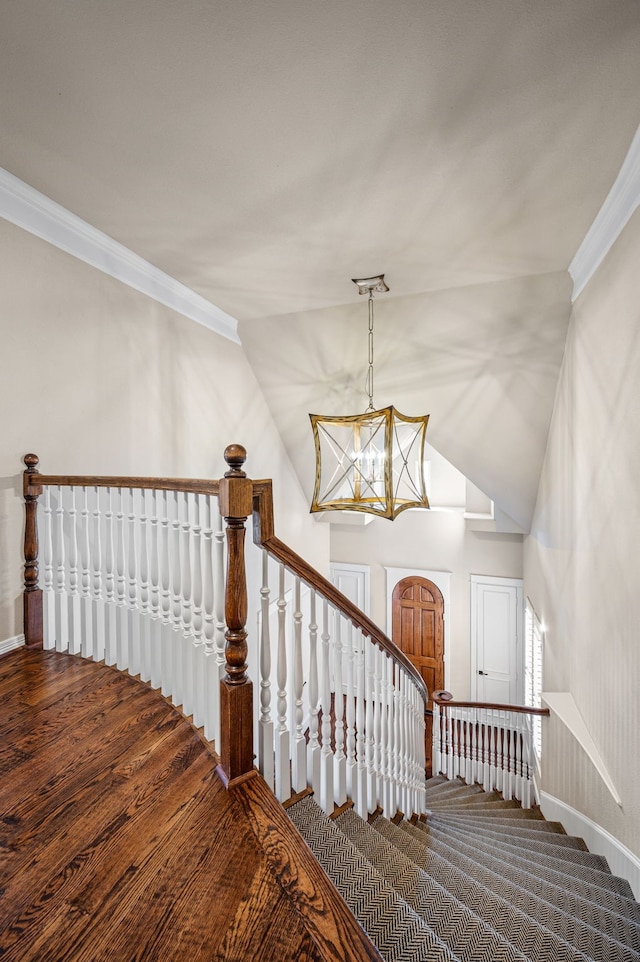 staircase with lofted ceiling, crown molding, and a chandelier