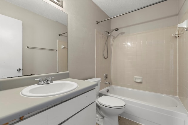 full bathroom with vanity, tiled shower / bath, toilet, and a textured ceiling