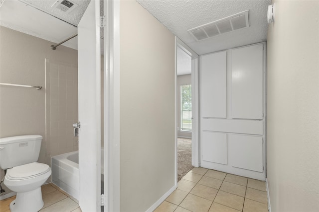 bathroom with a textured ceiling, tile patterned floors, toilet, and bathtub / shower combination