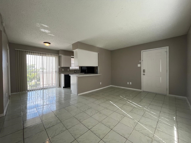 unfurnished living room featuring a textured ceiling and light tile patterned floors