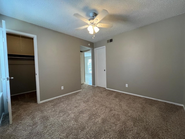 unfurnished bedroom featuring a closet, a spacious closet, carpet floors, and a textured ceiling