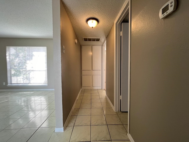 corridor with light tile patterned floors and a textured ceiling