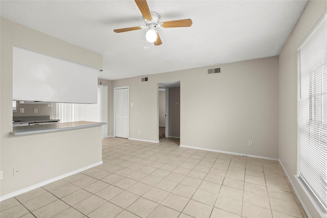 unfurnished living room featuring ceiling fan, a textured ceiling, and light tile patterned floors