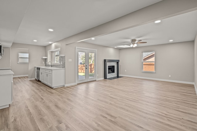 unfurnished living room with french doors, ceiling fan, light hardwood / wood-style floors, and sink