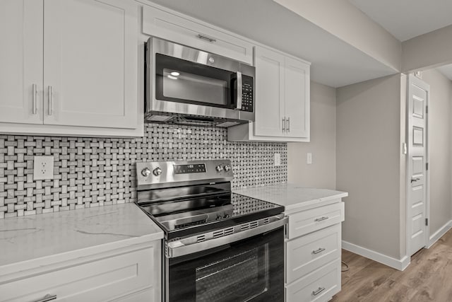 kitchen featuring appliances with stainless steel finishes, backsplash, light stone countertops, light hardwood / wood-style floors, and white cabinets