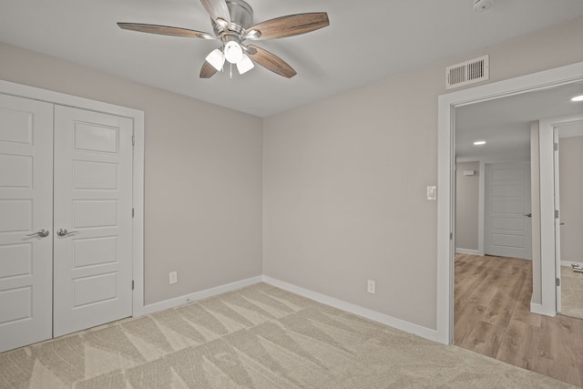 unfurnished bedroom featuring light colored carpet, ceiling fan, and a closet