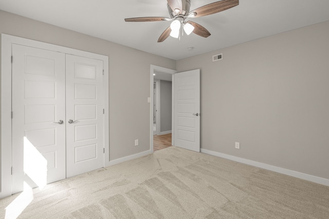 unfurnished bedroom featuring light colored carpet, ceiling fan, and a closet