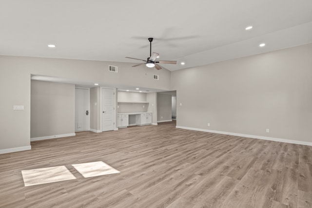 unfurnished living room with light hardwood / wood-style flooring, built in desk, vaulted ceiling, and ceiling fan