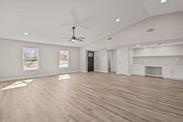 unfurnished living room featuring ceiling fan, built in desk, vaulted ceiling, and light wood-type flooring