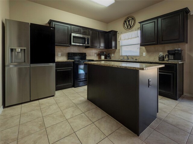 kitchen with light stone countertops, backsplash, black appliances, and a kitchen island