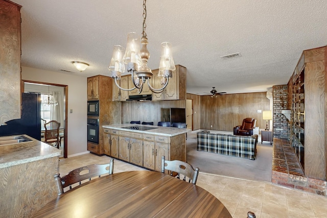 tiled dining space with a fireplace, wooden walls, ceiling fan with notable chandelier, and a textured ceiling