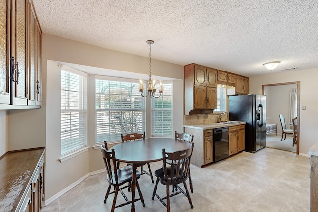 dining space featuring sink, a textured ceiling, and a notable chandelier