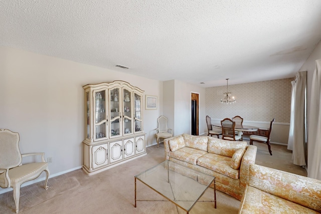 living room with light colored carpet, visible vents, a textured ceiling, and wallpapered walls