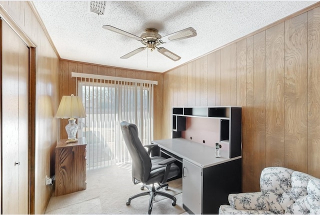 home office with carpet floors, crown molding, ceiling fan, wood walls, and a textured ceiling