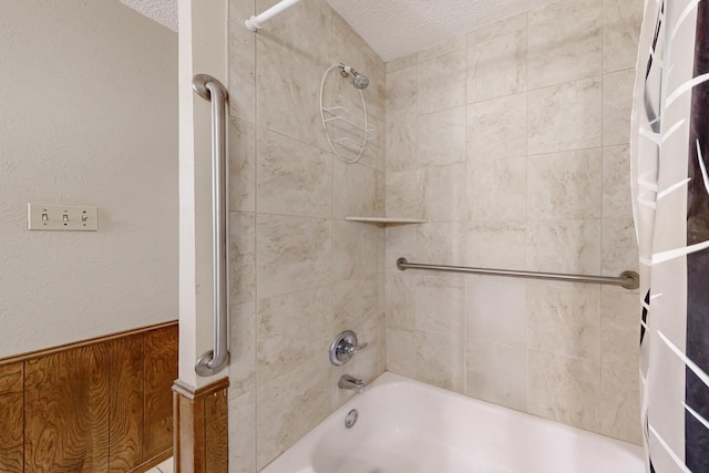 bathroom with bathtub / shower combination, a textured ceiling, and a textured wall