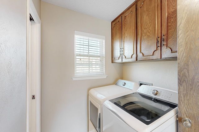 laundry area with cabinet space, a textured ceiling, and washing machine and clothes dryer