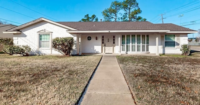 single story home with a front yard, brick siding, and roof with shingles