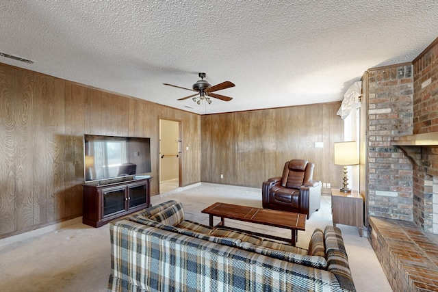 carpeted living room featuring ceiling fan, a fireplace, a textured ceiling, and wood walls