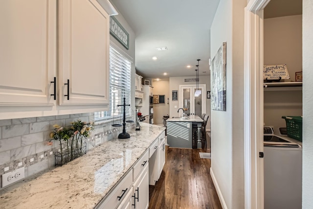 kitchen with white cabinetry, backsplash, light stone countertops, dark hardwood / wood-style flooring, and washer / clothes dryer