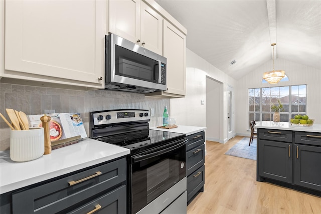 kitchen featuring pendant lighting, stainless steel appliances, white cabinets, decorative backsplash, and light wood-type flooring