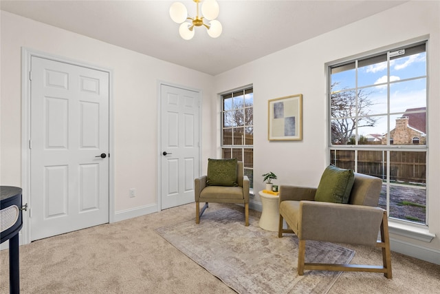 sitting room with an inviting chandelier, light colored carpet, and a wealth of natural light