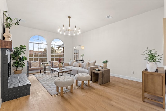 living room with a notable chandelier, a fireplace, and light hardwood / wood-style floors