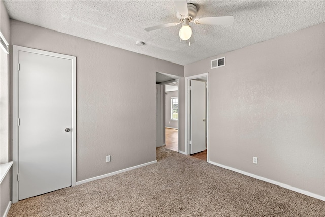 unfurnished bedroom with ceiling fan, carpet, and a textured ceiling