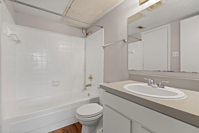 full bathroom with washtub / shower combination, hardwood / wood-style flooring, vanity, toilet, and a textured ceiling