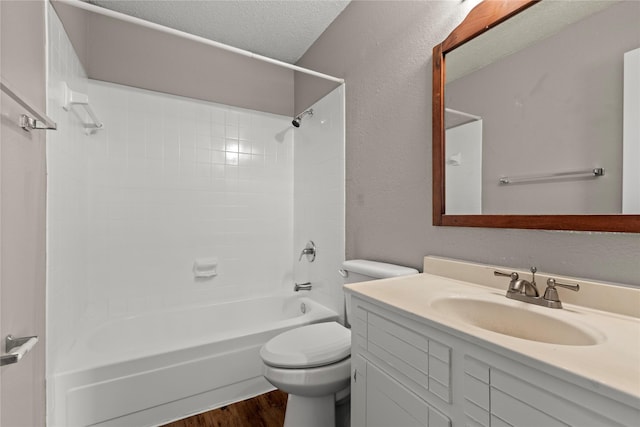 full bathroom with tiled shower / bath, hardwood / wood-style flooring, vanity, toilet, and a textured ceiling