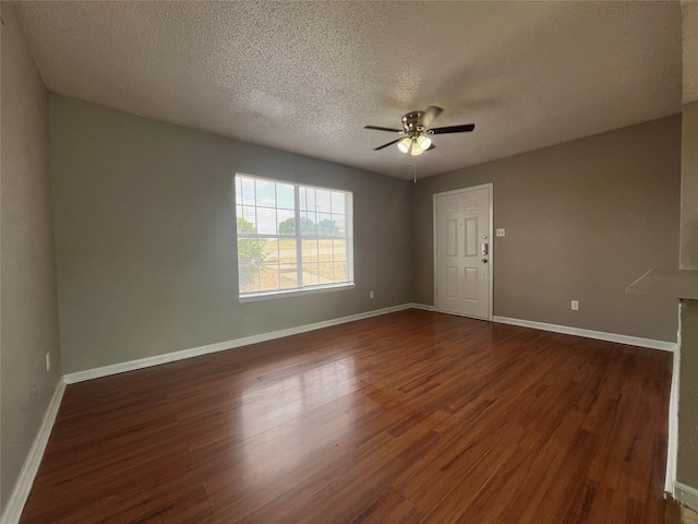 spare room with dark wood-type flooring, ceiling fan, and a textured ceiling