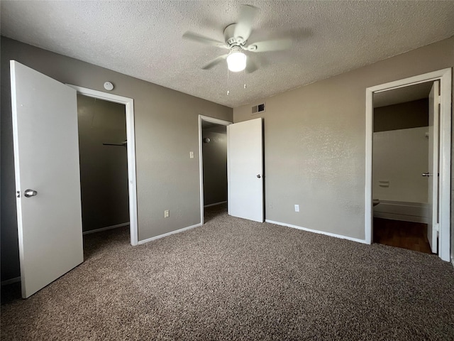 unfurnished bedroom featuring a closet, ensuite bathroom, carpet floors, and a textured ceiling