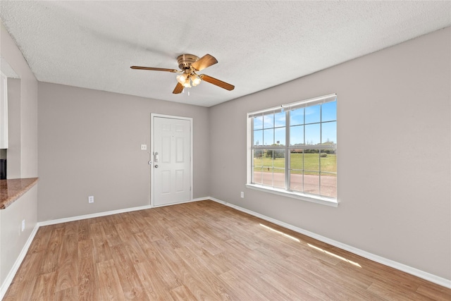 empty room with ceiling fan, a textured ceiling, and light wood-type flooring