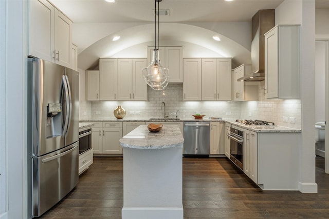 kitchen with appliances with stainless steel finishes, a kitchen island, white cabinetry, sink, and hanging light fixtures