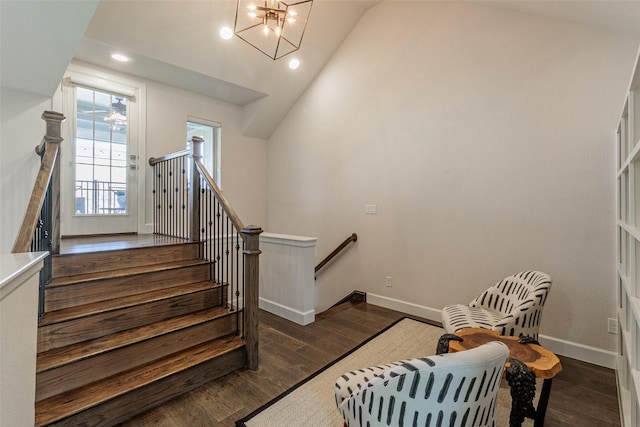 staircase with lofted ceiling, a notable chandelier, and hardwood / wood-style flooring