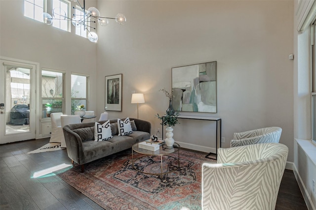 living room with an inviting chandelier, a healthy amount of sunlight, and dark hardwood / wood-style floors