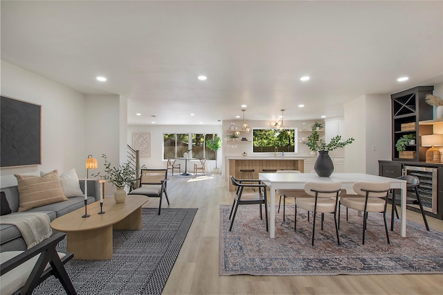 dining space with beverage cooler, sink, and light hardwood / wood-style flooring