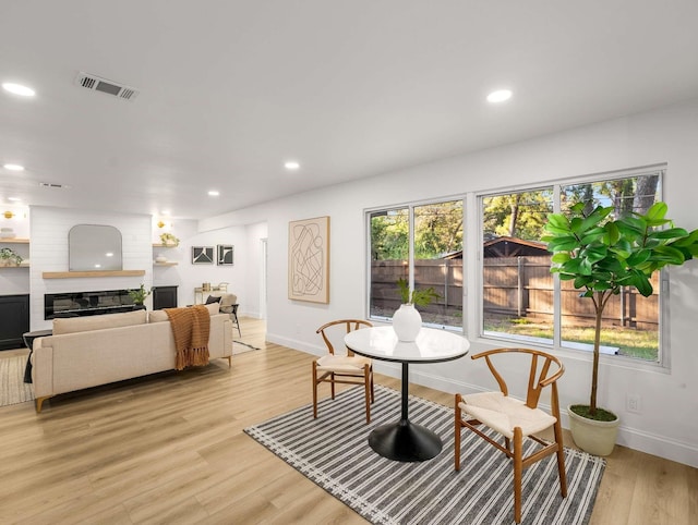 dining space featuring a large fireplace and light hardwood / wood-style flooring