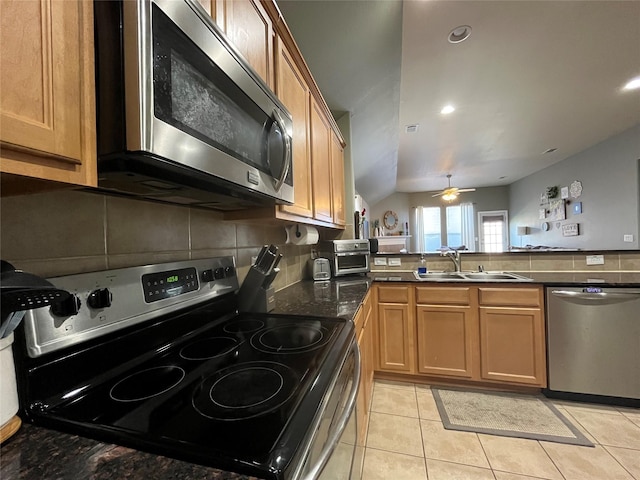 kitchen with appliances with stainless steel finishes, tasteful backsplash, sink, light tile patterned floors, and kitchen peninsula