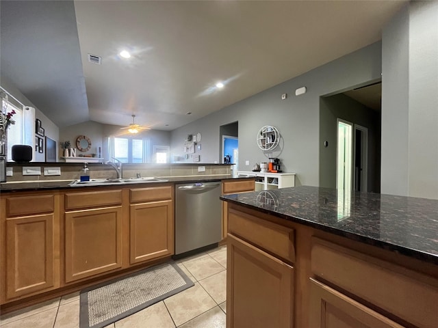 kitchen with lofted ceiling, sink, light tile patterned floors, dark stone countertops, and dishwasher