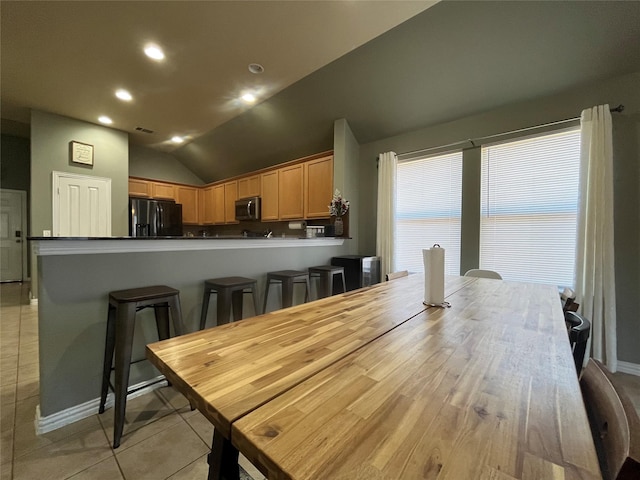 tiled dining room featuring vaulted ceiling