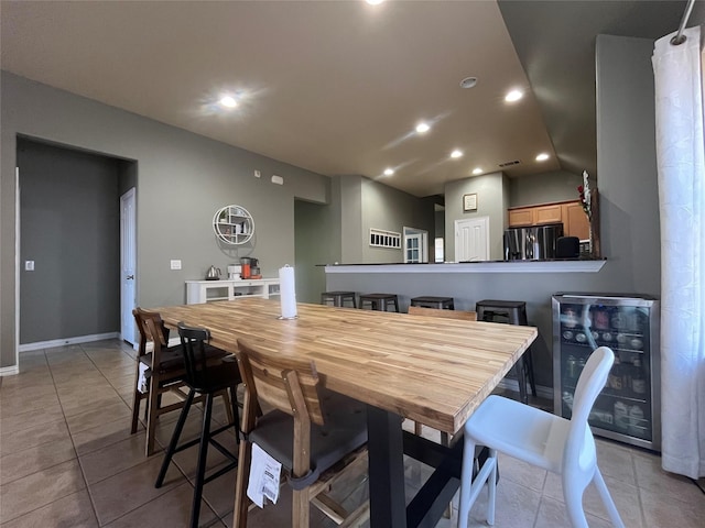 dining room featuring light tile patterned floors, vaulted ceiling, and beverage cooler