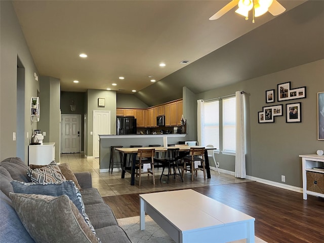 living room featuring hardwood / wood-style floors, vaulted ceiling, and ceiling fan